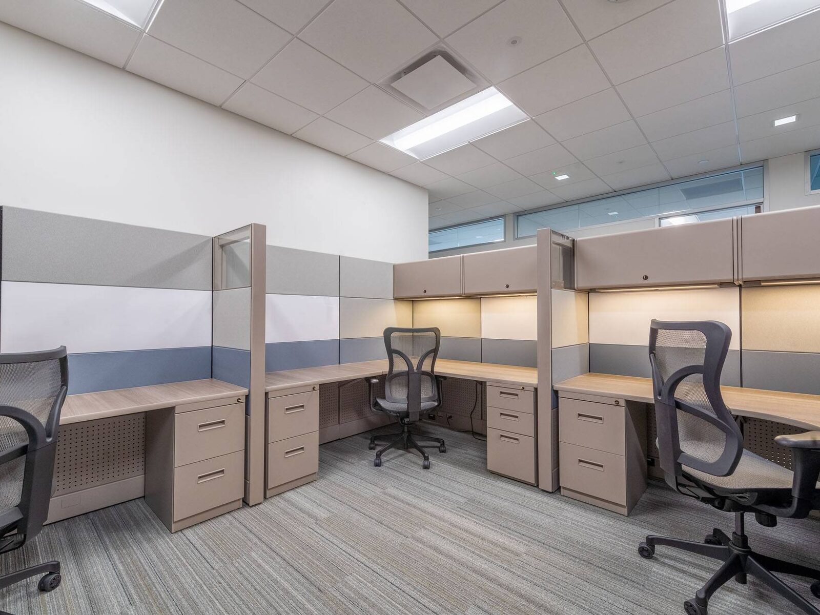 A row of newly installed cubicles with task lighting and mesh chairs